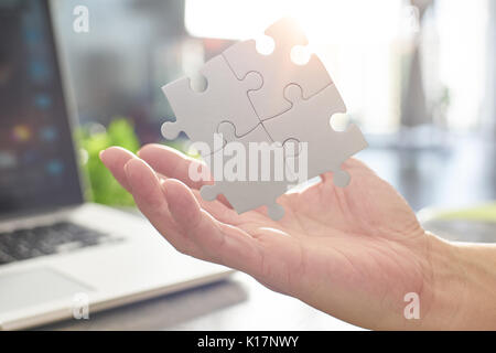 Giovane imprenditore che mostra il partenariato puzzle pezzo di puzzle con sun flare e blur sullo sfondo,il simbolo di associazione e connessione. strategia di business. Foto Stock