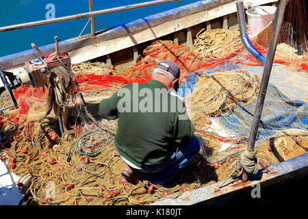 Sicilia, fisherman controlla le reti da pesca sulla sua barca nel porto di pesca di Castellammare del Golfo Foto Stock