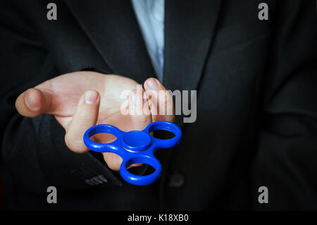 Strade blu spinner nella mano di un Uomo in camicia business e una camicia bianca. Potente spinner, Twister per le mani di intrattenimento giocattolo rotante. Antistr Foto Stock