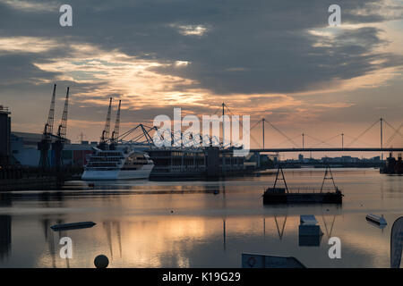 Silvertown, Newham, Londra, Regno Unito. Il 27 agosto 2017. Meteo REGNO UNITO: Bright bank holiday sunrise over London Docklands. Un giorno caldo e soleggiato è previsto. La stazione di London Victoria Dock con Excel exhibition centre e il Sunborn Yacht Hotel. Credito: WansfordPhoto/Alamy Live News Foto Stock