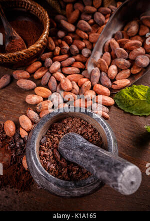 Primo piano della terra le fave di cacao in mortaio di pietra Foto Stock