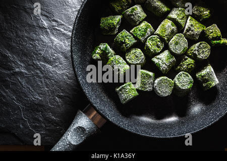 Congelati spinaci in bricchette in una padella in orizzontale Foto Stock