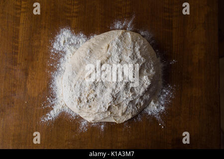 Infarinate focaccia di lievito di pasta di pane in appoggio sulla superficie di legno Foto Stock