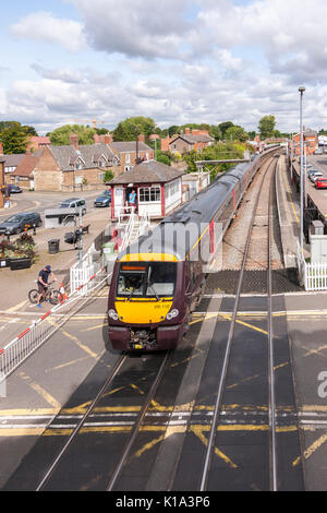 Treno diretto arcoss passaggio a livello in stazione a Oakham, Rutland.. U.K. Foto Stock