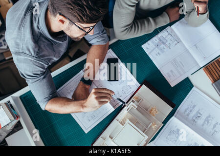 Vista dall'alto di due architetti maschile seduto in ufficio e lavorare sul progetto. Le persone creative che lavorano sulla nuova architettura modello di casa. Foto Stock