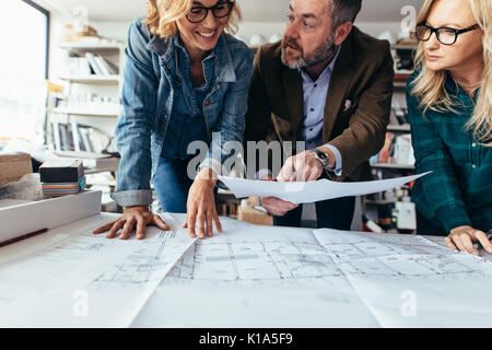 Un gruppo di persone di affari con blueprint per interni. Business di tre persone per discutere su un nuovo piano di costruzione. Foto Stock