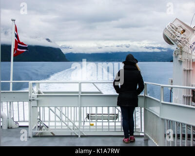 Signora sul ponte rivestite in tuta invernale godendo della vista panoramica di Snow capped montuosa intorno a Nord Gjord, Norvegia. Foto Stock