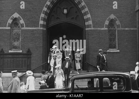 Gruppo di ben vestito di uomini e di donne e uomini in cappelli e tute le donne in cappelli, guanti e abiti, uscendo da una chiesa, auto parcheggiate davanti, Manchester, New Hampshire, 1937. Dalla Biblioteca Pubblica di New York. Foto Stock