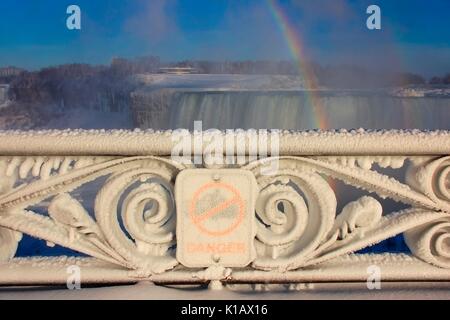 Decorativo recinzione in ferro coperto da uno strato spesso di nebbia congelata. Cascate del Niagara in background. Foto Stock