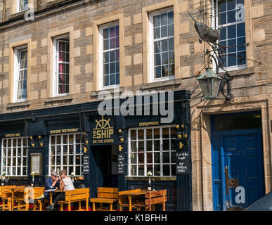 Leith ristorante, la nave sulla riva, con perseverare Modelli di nave emblema sulla parete e giovane seduto fuori nel sole, Edimburgo, Scozia, Regno Unito Foto Stock