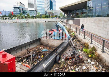 Nave di raccolta rifiuti sul canale della nave di Manchester; HIAB su una chiatta che raccoglie i detriti di plastica scartati, rifiuti, rifiuti, inquinati, inquinamento, Polistirene, e rifiuti tossici che vengono rimossi dalle rive dei canali di Salford Quays e Trafford, Greater Manchester, Inghilterra. REGNO UNITO Foto Stock