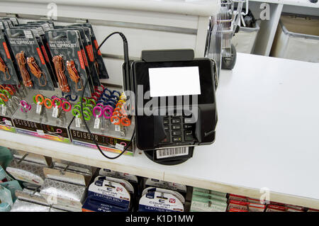 Un acquista un lettore di carte di credito con gli accessori che si trova accanto a un department store. Foto Stock