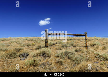 Una singola nuvola appesa sopra un recinto di filo spinato nel mezzo del deserto dello Utah. Foto Stock