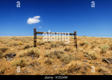 Una singola nuvola appesa sopra un recinto di filo spinato nel mezzo del deserto dello Utah. Foto Stock