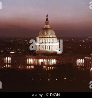 Una distanza lunga vista frontale del Campidoglio degli Stati Uniti, illuminata, scattata di notte, con le Luci lontane di case ed edifici in background, Washington DC, 1966. Foto Stock
