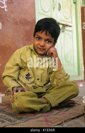 Ragazzo seduto fuori casa sua, Udaipur, Rajasthan, India Foto Stock