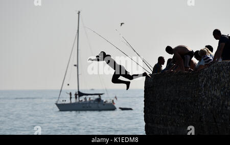 Brighton, Regno Unito. Il 27 agosto, 2017. I ragazzi del salto nel mare da un groyne sulla spiaggia di Brighton altrimenti noto come tombstoning nel caldo sole oggi come le temperature sono attesi per raggiungere alto come 28 gradi sopra la banca weekend che è un record per il mese di agosto . Bagnini locali e le guardie costiere avvertire che tombstoning può essere molto pericoloso come loro sono stati numerosi incidenti negli ultimi anni Credito: Simon Dack/Alamy Live News Foto Stock