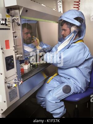 Un cdc scienziato conduce ricerche di laboratorio nel livello di biosicurezza 4 laboratorio, Atlanta, GA. labscience, un scienziato di cdc che indossa una tuta protettiva con il casco e la maschera per il viso è posizionato in corrispondenza di un flusso di aria cofano come egli conduce i suoi studi. Immagine cortesia cdc, 2002. Foto Stock