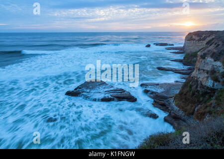 Scontrarsi onde lungo la costa della California a Santa Cruz al tramonto su un tardo autunno il giorno. Foto Stock