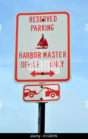 Il bianco e il rosso di parcheggio riservato per la Capitaneria di Porto segno con un traino di illustrazione e la doppia freccia. Foto Stock