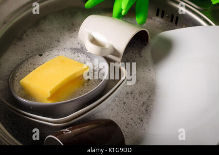 Lavello pieno di lavare i piatti pieni di piatto acqua e sapone. Foto Stock