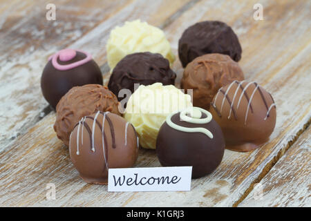 Welcome card con selezione di cioccolatini e praline su una superficie di legno Foto Stock