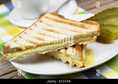 Due pezzi di pane tostato con il formaggio fuso sulla piastra bianca, primo piano Foto Stock
