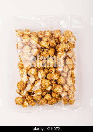 Caramello popcorn nella confezione di plastica su sfondo bianco Foto Stock