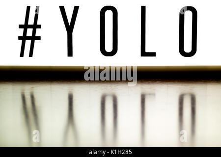 Una luce di bordo visualizza la frase #YOLO riflessa su legno Foto Stock