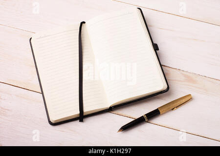 Aprire il notebook con una penna su un bianco tavolo di legno. Il lavoro in ufficio o in tema di diario. Foto Stock