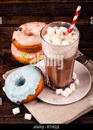 Frullato e ciambelle al buio su un sfondo di legno Foto Stock