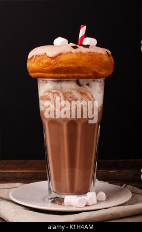 Frullato al cioccolato con panna montata e ciambella su un sfondo di legno Foto Stock