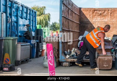 Un dipendente di sesso maschile circa per svuotare un wheely bin in un consiglio comunale / centro di riciclaggio di rifiuti / punta in Bourne, Lincolnshire, Inghilterra, Regno Unito. Foto Stock