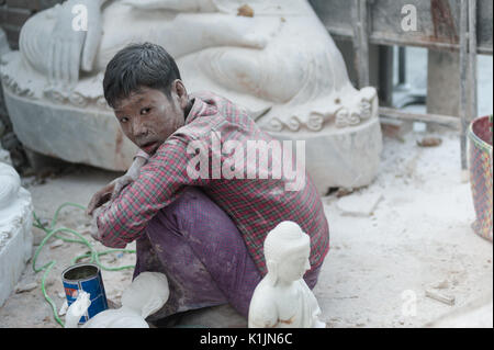 Un giovane uomo coperto di polveri bianche riposa in uno degli intagliatori di pietra workshop vicino Mahamuni Paya, Mandalay Myanmar. Foto Stock