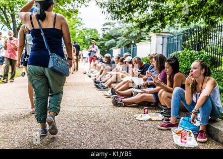 Washington DC, Stati Uniti d'America - 3 Luglio 2017: persone mangiare fast food sul marciapiede e camminare da carrelli di cibo sulla strada dal National Mall su Viale Indipendenza Foto Stock