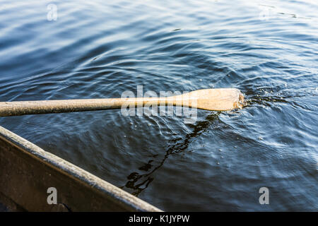 Vista dettagliata del remo pala dalla riga barca in movimento in acqua sul lago verde con increspature Foto Stock