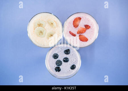 Vista superiore della banana e berry frappè in bicchieri sulla superficie blu Foto Stock