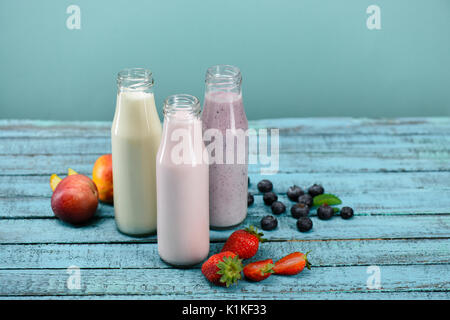 In casa fruttato frappè in bottiglie di vetro con gli ingredienti più freschi sul piano portapaziente su blu Foto Stock