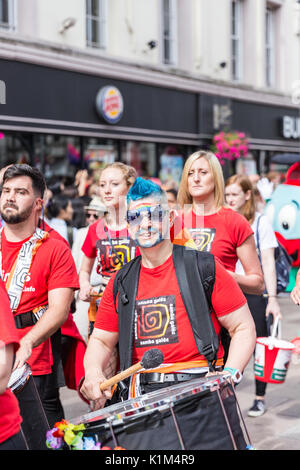 Un uomo con capelli blu e un grande tamburo marche in Cardiff Pride Parade 2017 Foto Stock