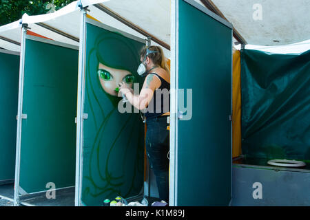 Grafitti artista vernice spray su un wc parete di un cubicolo in preparazione per notare Hill Carnevale. Foto Stock