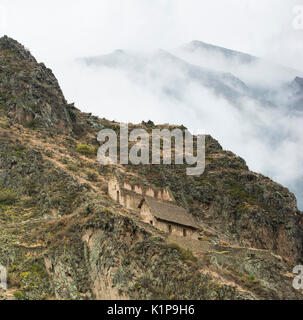Casa di Ollantaytambo e granaio con enormi nubi di montagna, Perù Foto Stock