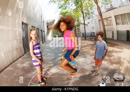 I bambini saltare su di una corda elastica sorridente e felice con parentesi ragazza africana in aria Foto Stock