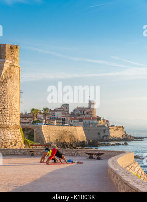 Un uomo e una donna pratica yoga al mattino presto si affaccia Antibes, Cote d'Azur, in Francia Foto Stock