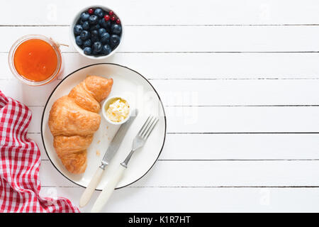 La prima colazione continentale croissant, burro, mirtilli e marmellata su bianco tavolo in legno sfondo. top visualizzare e copiare lo spazio per testo Foto Stock