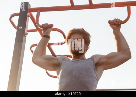 Tirare ups in orizzontale a barre. I giovani adulti barbuto redhead uomo facendo tirare ups. Per esterno Foto Stock