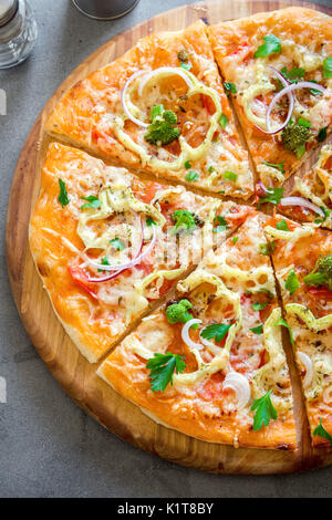 Pizza vegetariana sul calcestruzzo rustico sfondo. La Pizza italiana con verdure e formaggio vicino. Foto Stock