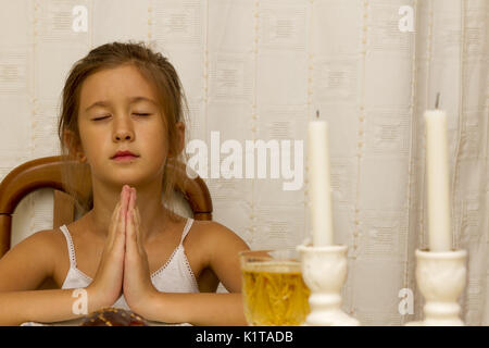 Ragazza ebrea dice la benedizione su di illuminazione il sabbath candele prima di shabbat cena della vigilia. interna Foto Stock