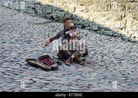 TALLINN, Estonia, 10 agosto: un musicista di strada a suonare il violino mentre è seduto su una pavimentazione di ciottoli nella città vecchia di Tallinn, 10 agosto 2017. Foto Stock