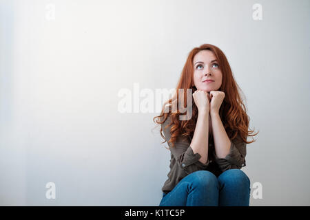 Ritratto di una giovane e bella donna pensare, isolati su sfondo bianco Foto Stock