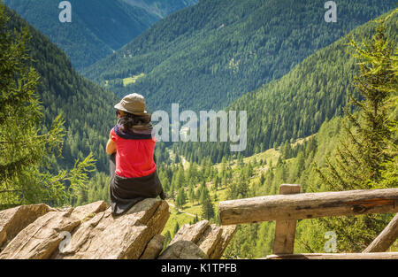 Traveler giovane donna in piedi sulla cima della montagna e godersi vista valle. Valle di Rabbi, Trentino Alto Adige, Italia settentrionale Foto Stock